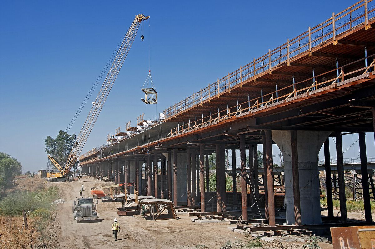 Falsework propping the deck of a bridge under construction, with a crawler crane working alongside