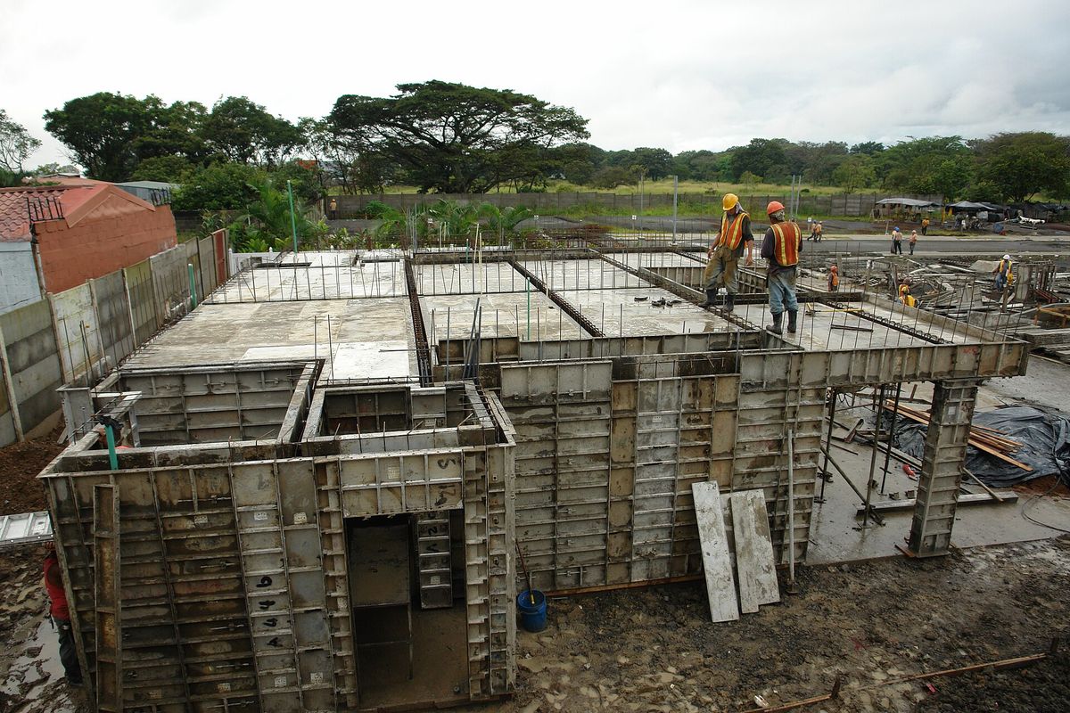 Steel wall formwork panels set out on a reinforced concrete slab, with operatives working above them